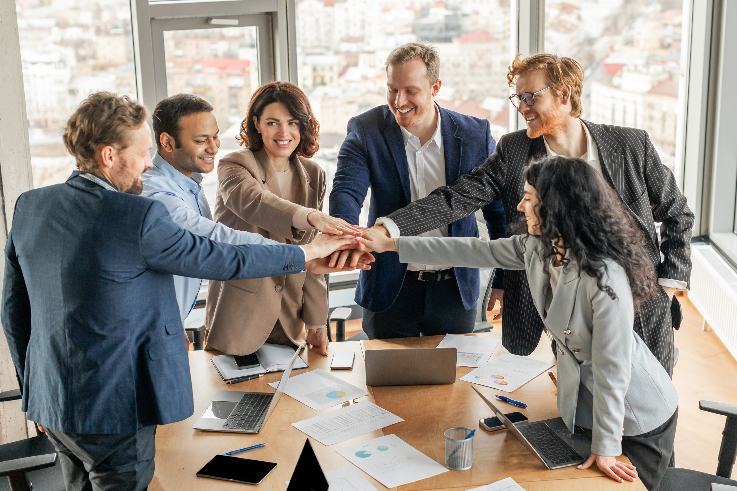 Diverse Business Team Placing Hands Together in Modern Office Meeting